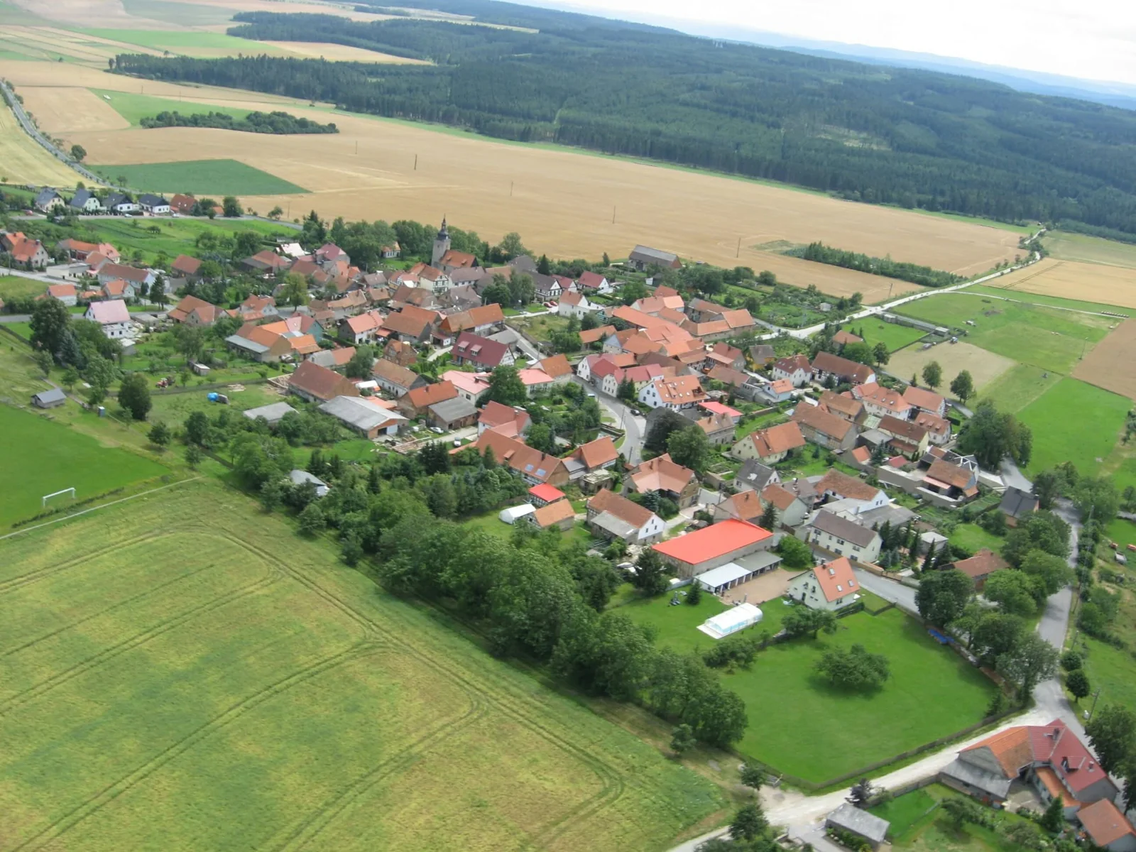 Luftaufnahme von Rittersdorf mit der Dorfkirche, Häusern, Feldern und Wald